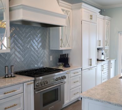 Bali Tide Remodel kitchen in Gulf Breeze, Florida featuring custom white cabinetry, paneled refrigerator and freezer, professional-style range, built-in coffee bar, and gold hardware in an open coastal floor plan.