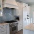 Bali Tide Remodel kitchen in Gulf Breeze, Florida featuring custom white cabinetry, paneled refrigerator and freezer, professional-style range, built-in coffee bar, and gold hardware in an open coastal floor plan.