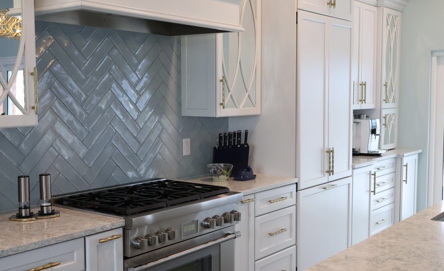 Bali Tide Remodel kitchen in Gulf Breeze, Florida featuring custom white cabinetry, paneled refrigerator and freezer, professional-style range, built-in coffee bar, and gold hardware in an open coastal floor plan.
