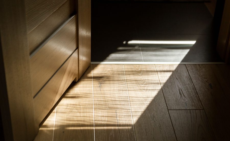 Luxury wood flooring in a 30A home with sunlight creating patterned shadows